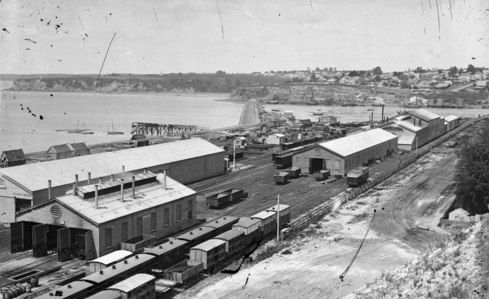 Historic railway sheds, trains and tracks beside Auckland's waterfront before the present station was built.