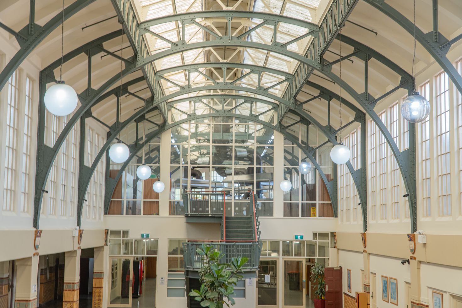 Looking up into the Grand Hall's riveted steel arches, glazed roof and hanging globe lights.