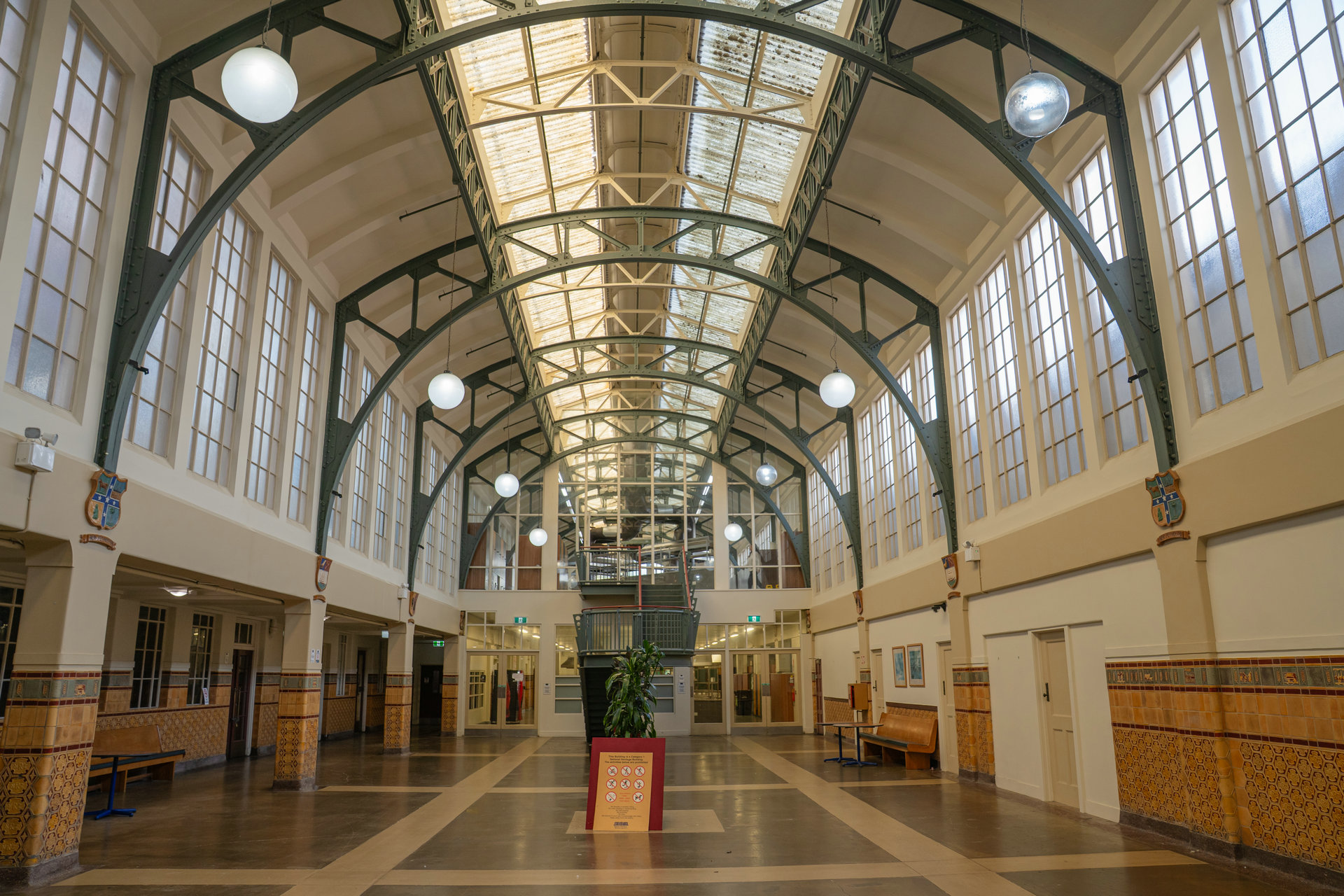 Wide contemporary view of the hall's steel arches, heritage windows and tiled walls.