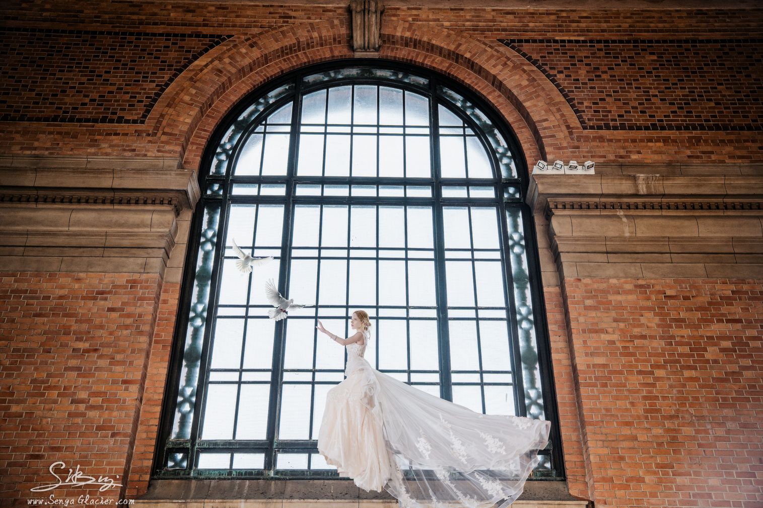 A bride framed by the monumental arched window of the Grand Foyer.