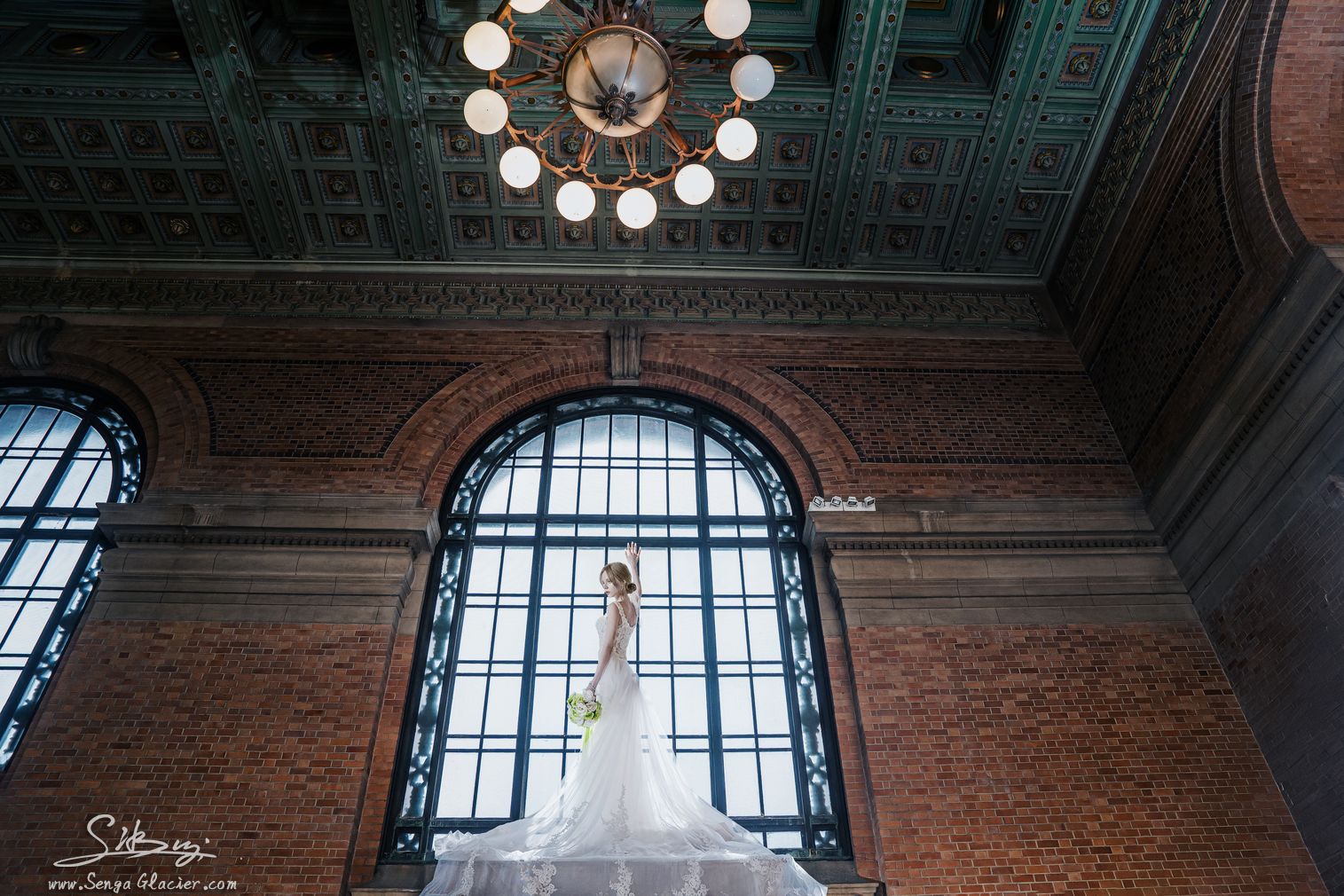 A bride beneath the chandelier and arched window of Grand Central Hotel's Grand Foyer.