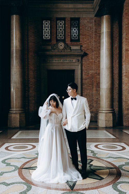 A newly married couple standing on the patterned terrazzo floor between the Grand Hall columns.