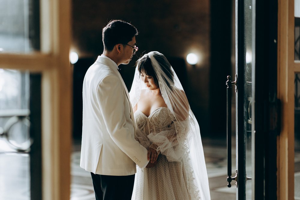 A couple sharing a quiet moment in a doorway filled with soft natural light.