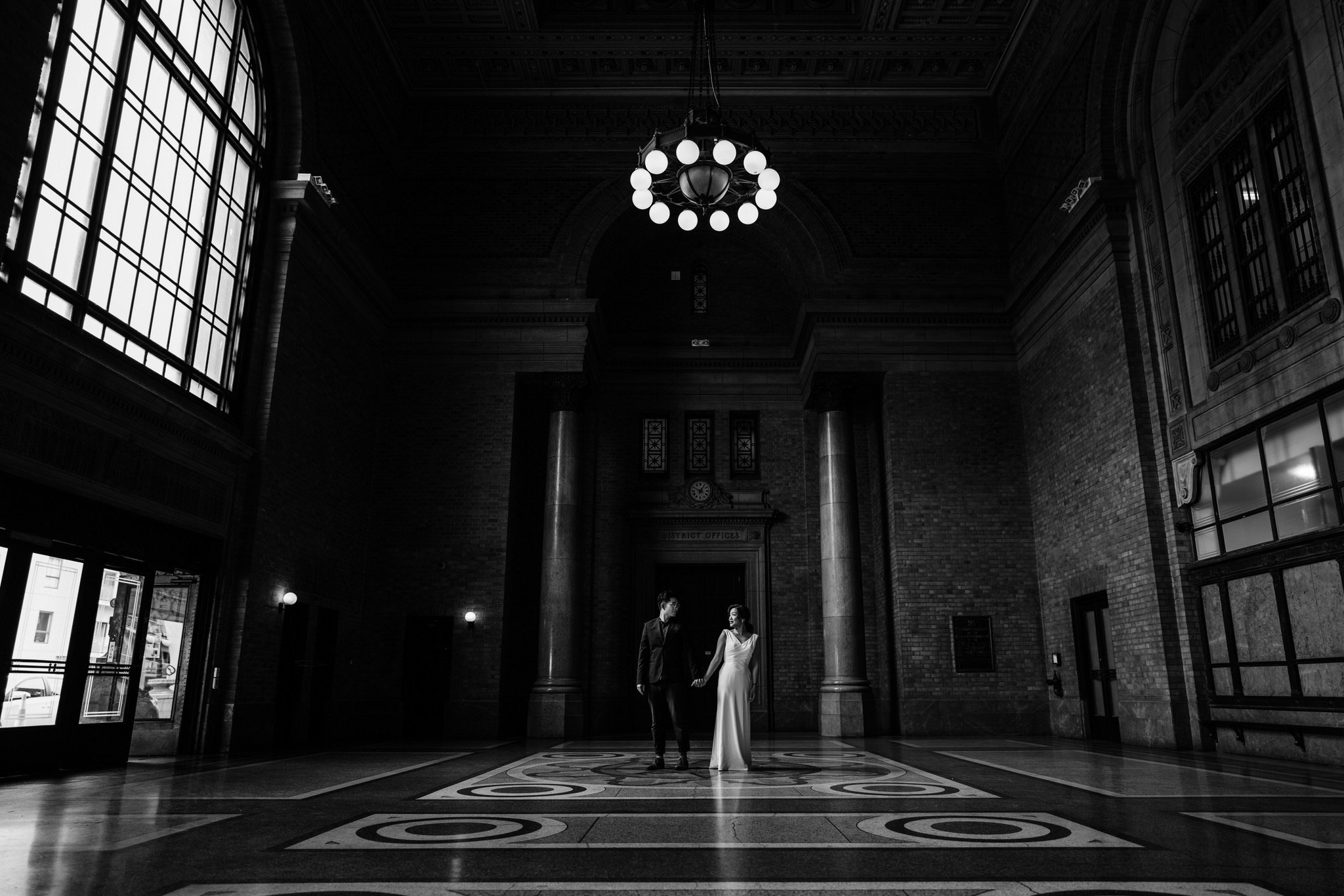A wedding couple standing beneath the chandelier in the monumental Grand Foyer.